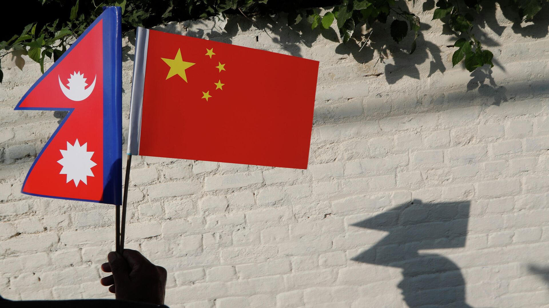 A Nepalese man holds Chinese and Nepalese flags as he waits to welcome Chinese president Xi Jinping in Kathmandu, Nepal, Saturday, Oct 12, 2019.  - Sputnik International, 1920, 23.02.2022