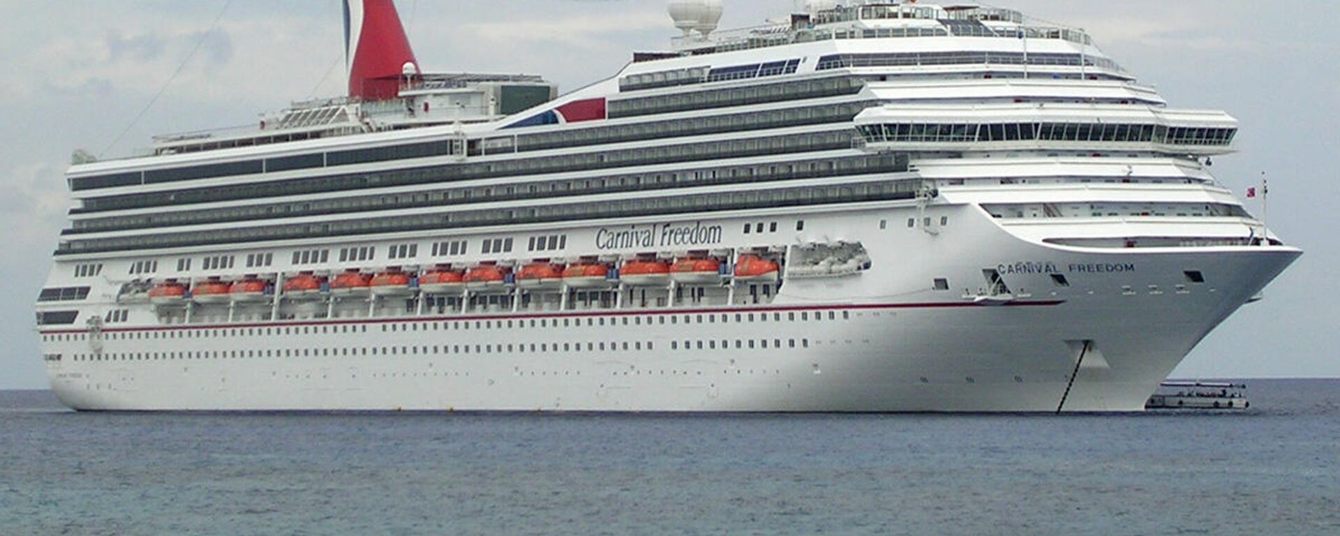 Carnival Freedom is in the harbor at George Town, Grand Cayman. It is one of Carnival's ships entering cruise service in 2007. It has a lot of balconies. The ship is 952 ft (290 m) long. It lists capacity of carries 2,900 passengers, which might be the meximum if extra capacity in cabins is used. I took this photo from the shore. - Sputnik International, 1920, 25.12.2021