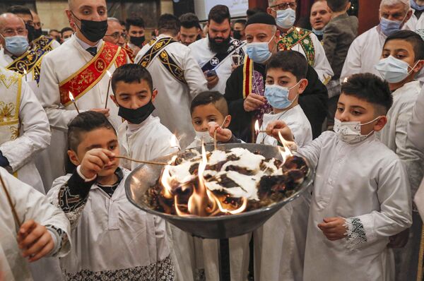Young altar servers light up their candles during the Christmas Eve mass at the Syriac Orthodox Church of Um al-Noor in Arbil, the capital of the autonomous Kurdish region in northern Iraq, on 24 December 2021. - Sputnik International