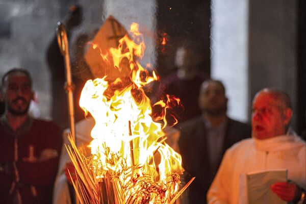 The mitre (hat) and crosier (pastoral staff) of Chaldean Catholic Archbishop of Basra Habib Nafali are seen behind a bonfire during the Christmas eve mass at the Church of Saint Teresa of the Child Jesus in the southern Iraq city of Basra on 24 December 2021. - Sputnik International
