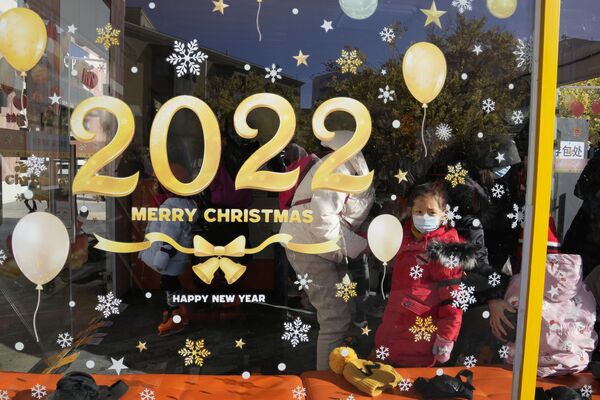 A child wearing a mask looks out from a window promoting the 2022 Christmas holiday at a mall in Beijing, China, Saturday, 25 December 2021.  - Sputnik International