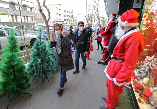 A man dressed as Santa greets Iranians as they walk past a shop selling Christmas decorations in the capital Tehran on 24 December 2021.  - Sputnik International