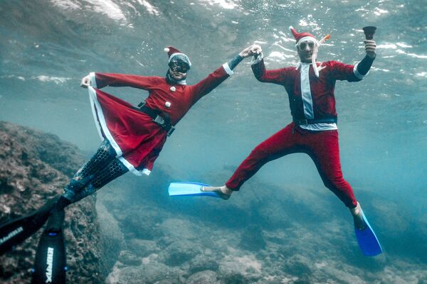 Freedivers dressed in Saint Nicholas (Santa Claus) costumes pose for a picture while submerged underwater off the coast of Lebanon's northern city of Batroun on Christmas eve on 24 December 2021.  - Sputnik International