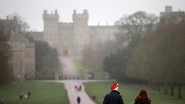 A man wears a Christmas hat as he walks along the Long Walk in front of Windsor Castle in Windsor, Britain, on 24 December 2021. - Sputnik International