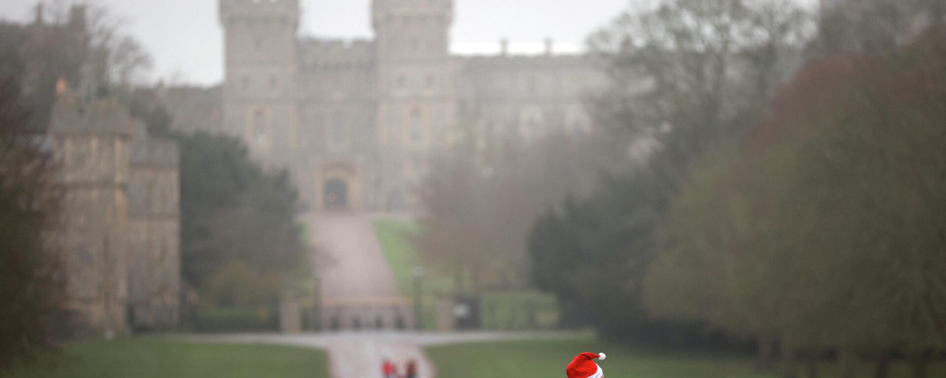 A man wears a Christmas hat as he walks along the Long Walk in front of Windsor Castle in Windsor, Britain, on 24 December 2021. - Sputnik International, 1920, 27.12.2021