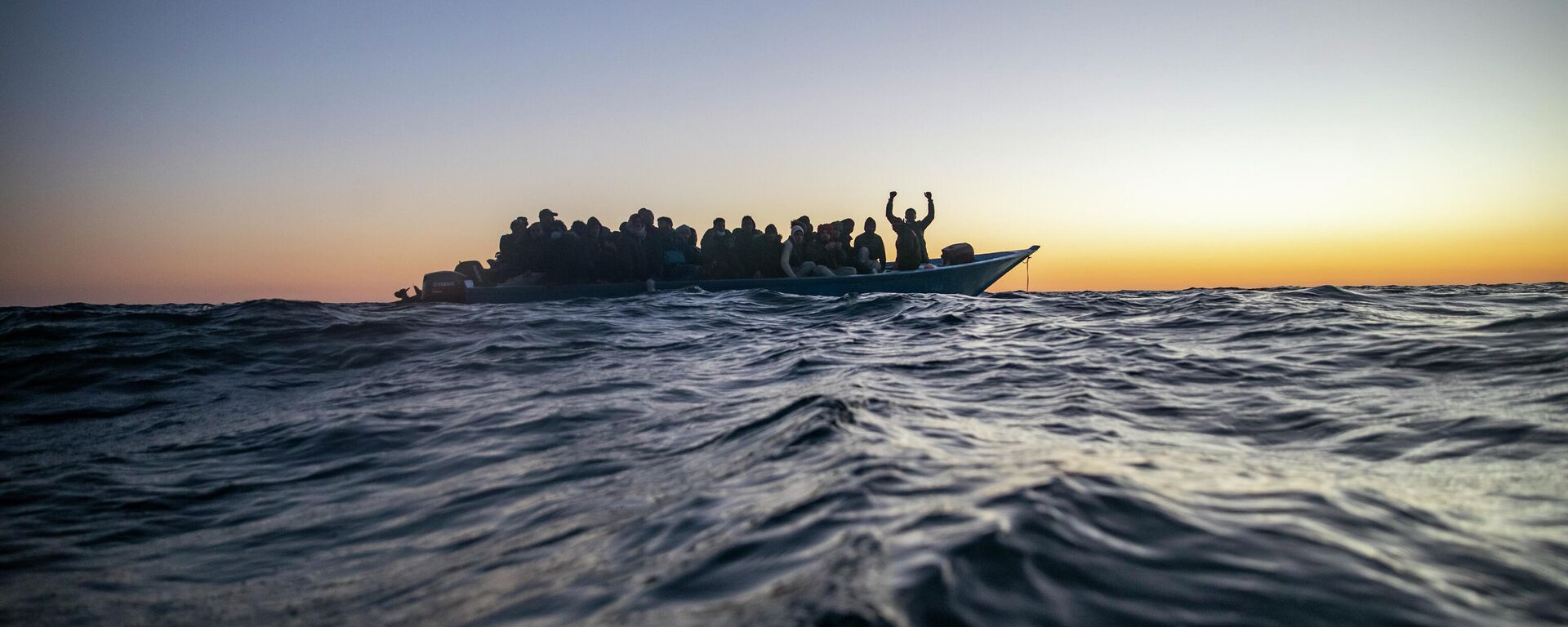 Migrants and refugees of various African nationalities wait for assistance aboard an overcrowded wooden boat in the Mediterranean Sea 122 miles off the coast of Libya as aid workers on the Spanish search and rescue vessel Open Arms approach on Feb. 12, 2021. - Sputnik International, 1920, 26.12.2021