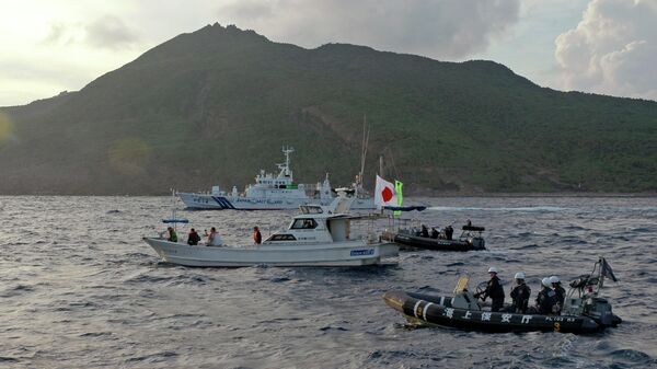 A Japanese Coast Guard boat and vessel sail alongside Japanese activists' fishing boat, not in photo, warning the activists away from a group of disputed islands called Senkaku by Japan and Diaoyu by China on Aug. 18, 2013 - Sputnik International