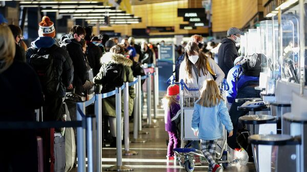 A family works through check-in at Alaska Airlines ticketing after dozens of flights were listed as cancelled or delayed at Seattle-Tacoma International Airport (Sea-Tac) in Seattle, Washington, U.S. December 27, 2021. - Sputnik International