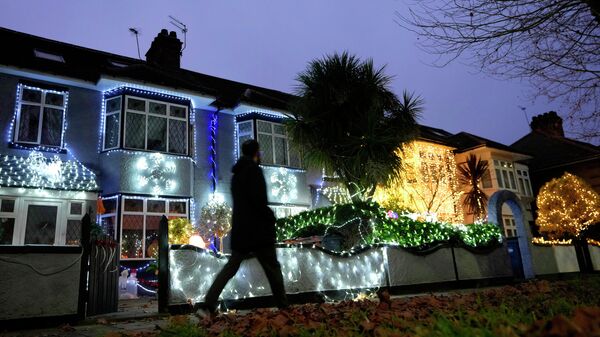 A pedestrian passes houses decorated with seasonal lights in London, Thursday, Dec. 23, 2021 - Sputnik International