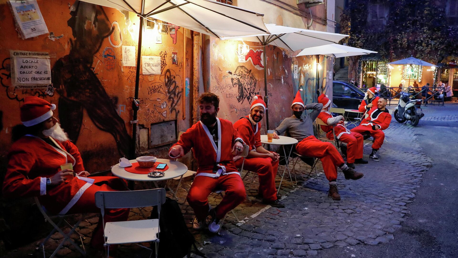 Men dressed in Santa suits sit in outdoor tables in Trastevere one day before Italy goes back to a complete lockdown as part of efforts put in place to curb the spread of the coronavirus disease (COVID-19), in Rome, Italy, December 23, 2020. - Sputnik International, 1920, 30.12.2021