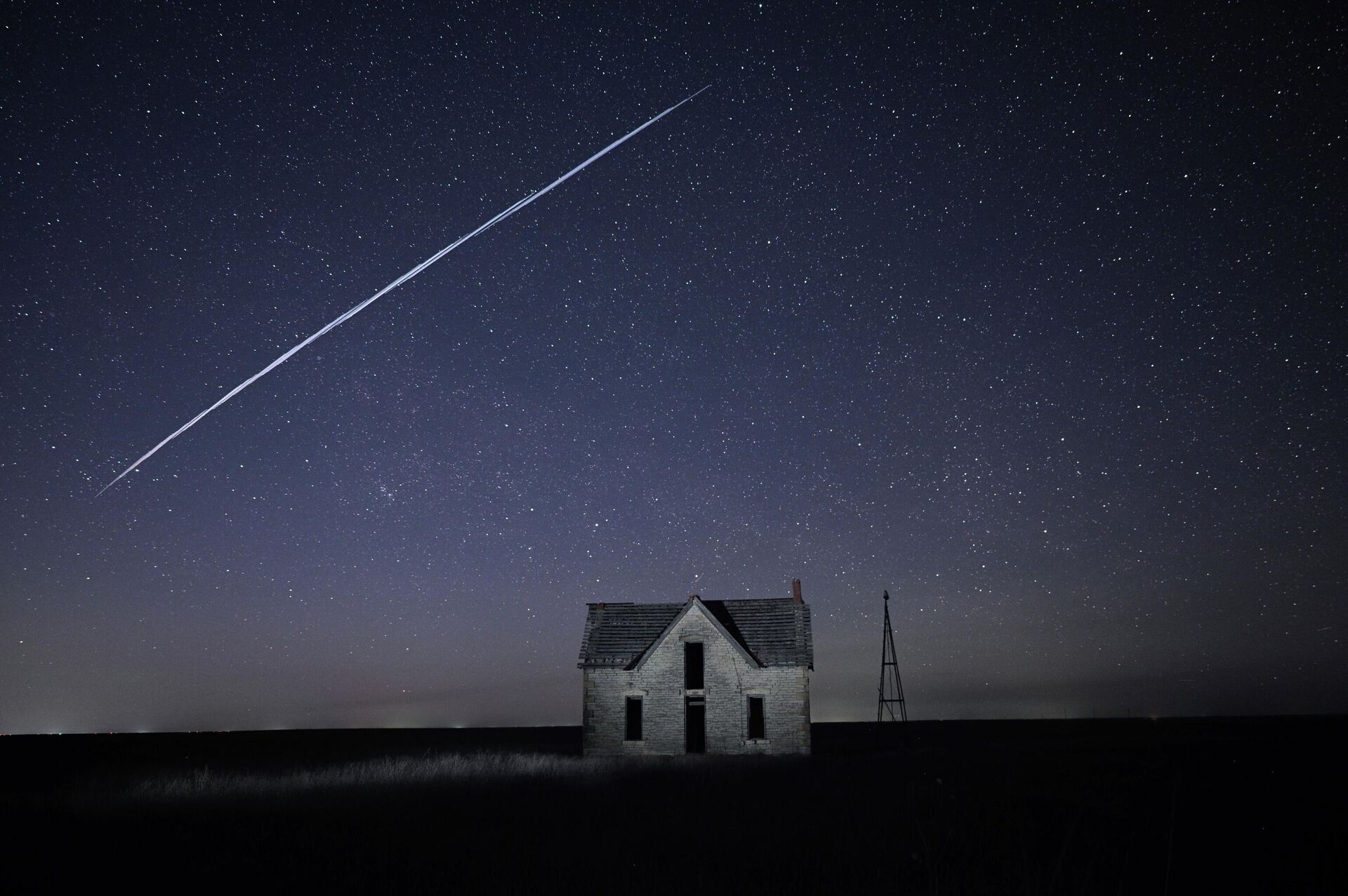 In this photo made with a long exposure, a string of SpaceX StarLink satellites passes over an old stone house near Florence, Kan., on Thursday, May 6, 2021. - Sputnik International, 1920, 18.10.2022