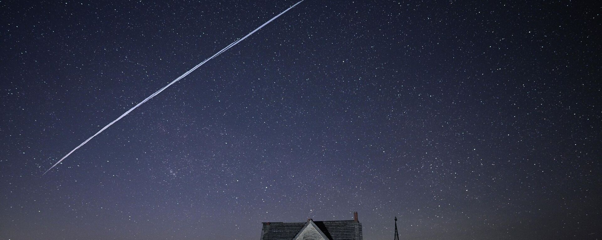 In this photo made with a long exposure, a string of SpaceX StarLink satellites passes over an old stone house near Florence, Kan., on Thursday, May 6, 2021. - Sputnik International, 1920, 11.09.2022