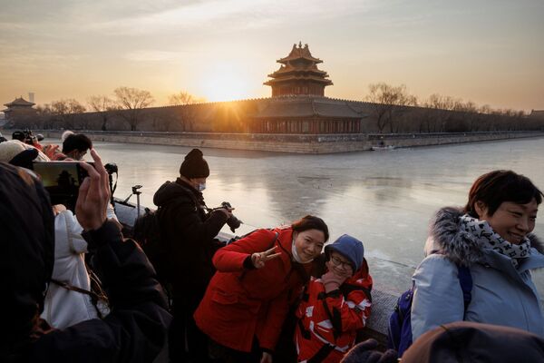 People pose for pictures as the first sun of the year rises above the Forbidden City in Beijing, China as the city prepares to host the Winter Olympics, 1 January 2022. - Sputnik International