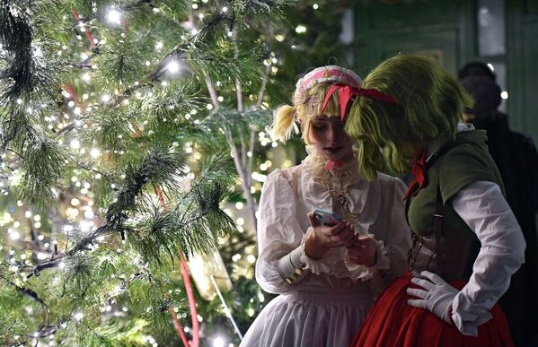 Girls wearing costumes watch something on a cell phone during New Year celebrations in Moscow.  - Sputnik International