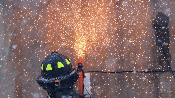 A firefighter cuts holes into a burning shipping container to spray water inside from different angles, a day after evacuation orders, in Louisville, Colorado - Sputnik International