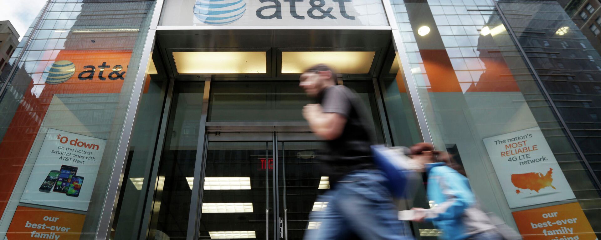 FILE - In this Oct. 21, 2014, file photo, people pass an AT&T store along New York's Madison Avenue. The nation's largest cellphone providers will pay a combined $116 million under a settlement approved Thursday, Sept. 24, 2020, in a California lawsuit alleging that they overcharged government customers for wireless services over more than a decade. Verizon will pay $68 million and AT&T Mobility $48 million to settle claims that they violated cost-saving agreements with nearly 300 state and local governments.  - Sputnik International, 1920, 04.01.2022