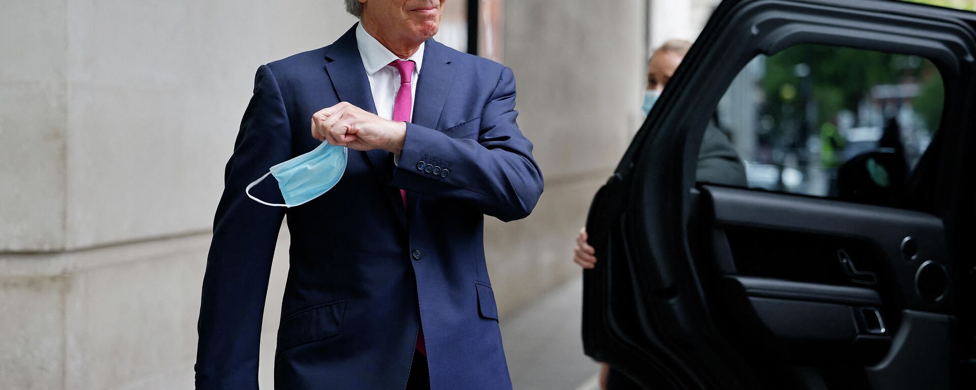 Former British Prime Minister Tony Blair, removes his disposable face covering worn due to Covid-19, to pose for a photograph as he leaves the BBC in central London on June 6, 2021, after appearing on the BBC political programme The Andrew Marr Show - Sputnik International, 1920, 06.01.2022
