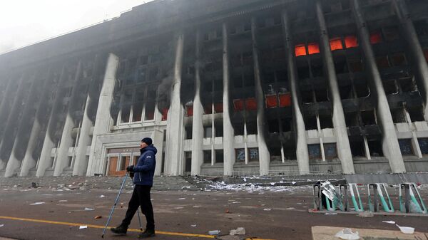 A man stands in front of the mayor's office building which was torched during protests triggered by fuel price increase in Almaty, Kazakhstan January 6, 2022 - Sputnik International