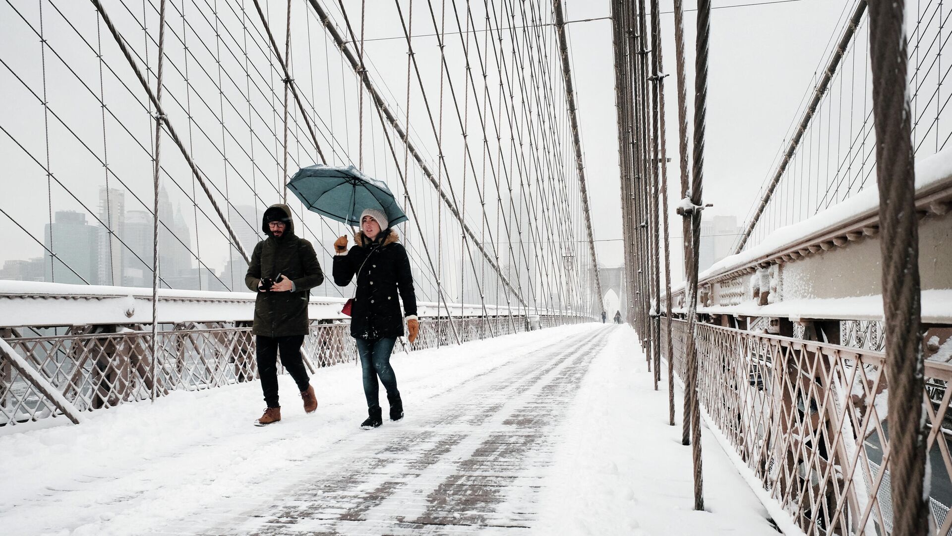 People walk through the snow on the Brooklyn Bridge in Manhattan on January 07, 2022 in New York City. New York City and much of the tri-state region received over four inches of snow in what is the first significant snow accumulation of the season. - Sputnik International, 1920, 07.01.2022