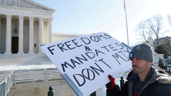 A lone protester stands outside the U.S. Supreme Court as it hears arguments against the Biden administration's nationwide vaccine-or-testing COVID-19 mandates, in Washington, U.S., January 7, 2022.  - Sputnik International