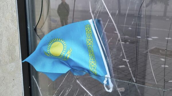 A Kazakh state flag is seen at the broken window of the Kaspi Bank branch following the protests triggered by fuel price increase in Almaty, Kazakhstan January 6, 2022. - Sputnik International