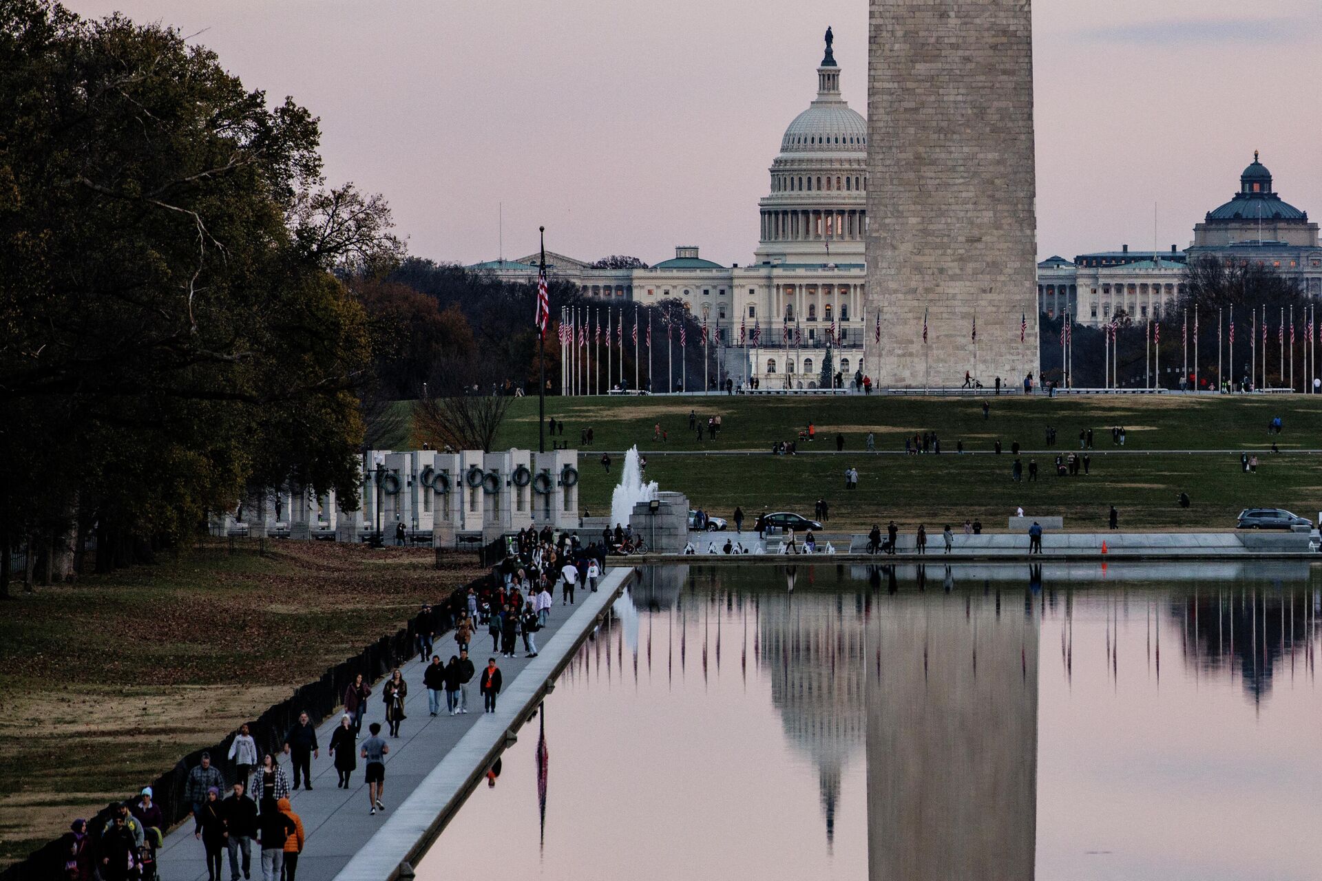 The U.S. Capitol Building is seen past the Washington Monument as people walk around the Reflecting Pool on the National Mall as the sun sets on November 28, 2021 in Washington, DC. President Biden returned to Washington after spending the Thanksgiving Holiday with family in Nantucket and immediately met with members of his medical team to discuss the newly discovered Omicron variant of the coronavirus. - Sputnik International, 1920, 13.01.2022