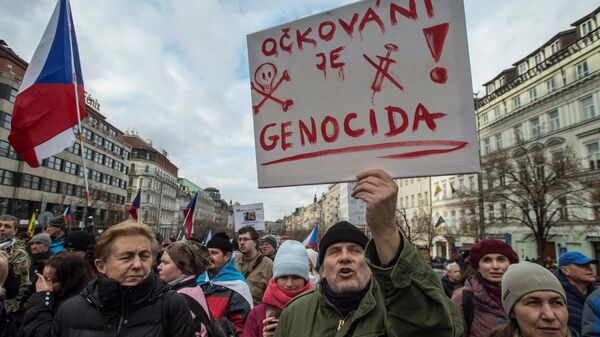 The lettering on a placard reads 'Vaccination is genocide' and 'Defend your children' as demonstrators march with the Czech national flag as they take part in a protest against compulsory vaccination against the coronavirus (Covid-19) in Prague on January 9, 2022, during the ongoing pandemic. - - Sputnik International