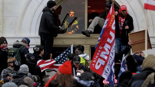 A mob of supporters of then-U.S. President Donald Trump climb through a window they broke as they storm the U.S. Capitol Building in Washington, U.S., January 6, 2021 - Sputnik International