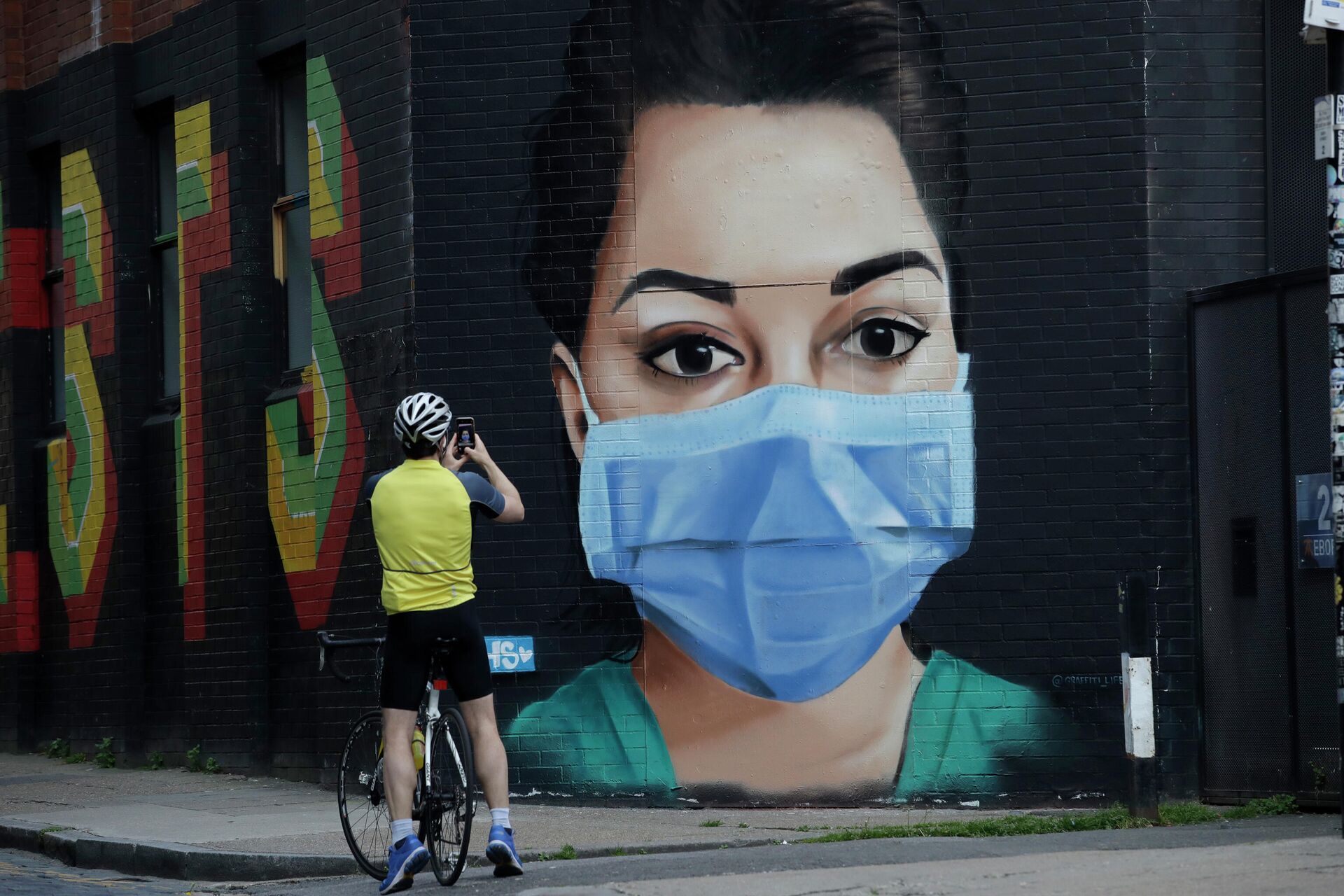 A cyclist takes a picture of a recently painted mural by professional street artist David Speed and the Graffiti Life collective to show appreciation for the people who work in the NHS (National Health Service), in east London, Thursday, April 23, 2020 - Sputnik International, 1920, 06.11.2022