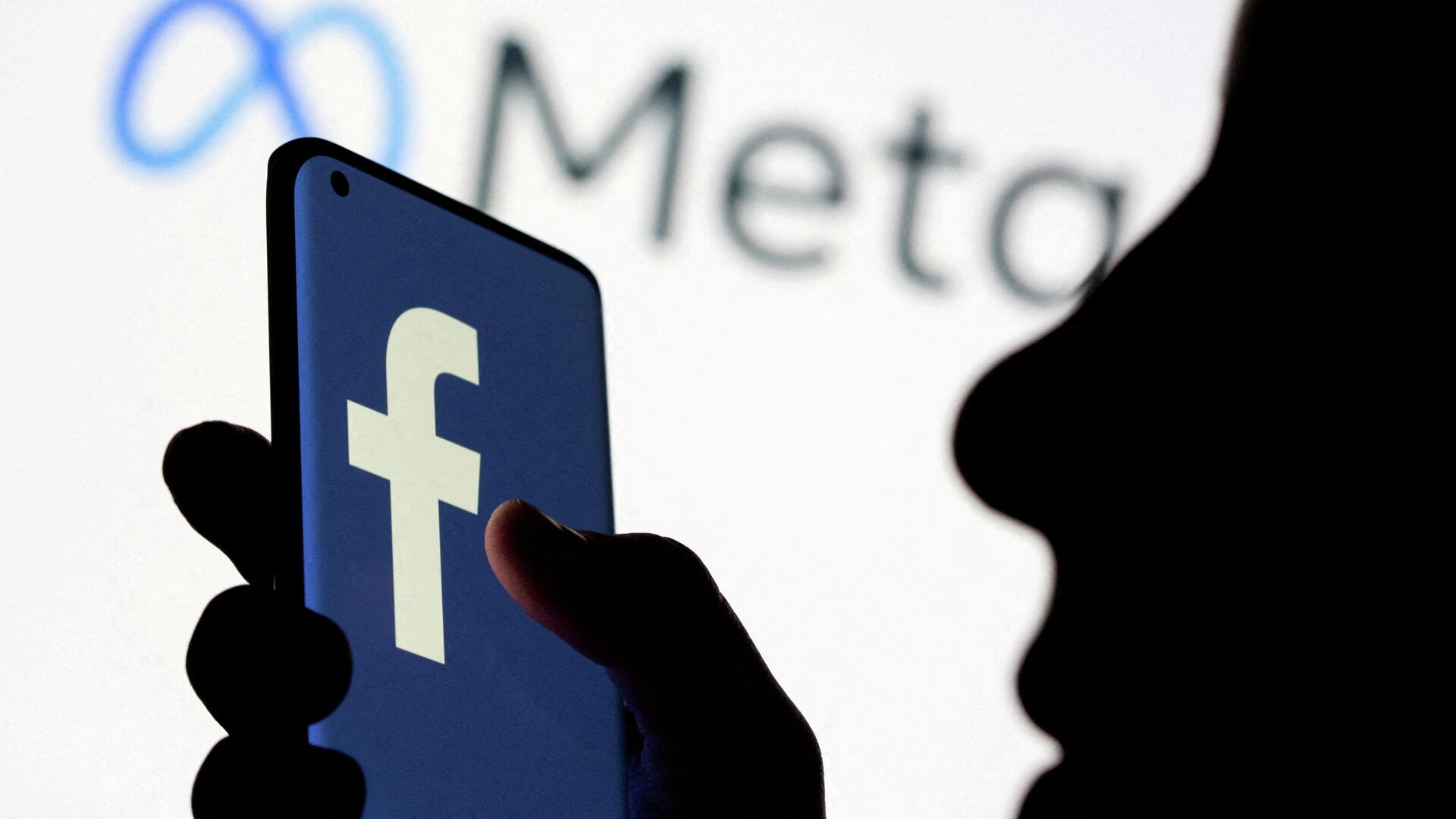 A woman holds smartphone with Facebook logo in front of a displayed Facebook's new rebrand logo Meta in this illustration picture taken October 28, 2021 - Sputnik International, 1920, 17.01.2022