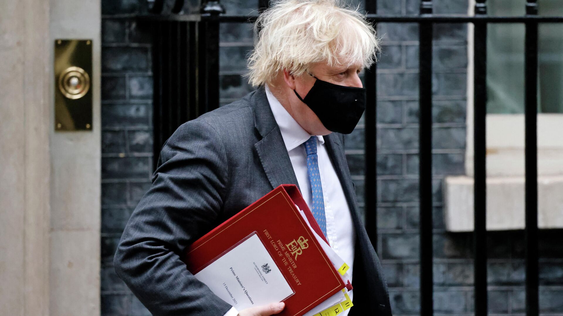 Britain's Prime Minister Boris Johnson, wearing a face covering to stop the spread of coronavirus, carries his notes in a ministerial folder as he leaves from 10 Downing Street in central London on December 15, 2021, to take part in the weekly session of Prime Minister Questions (PMQs) at the House of Commons - Sputnik International, 1920, 28.01.2022