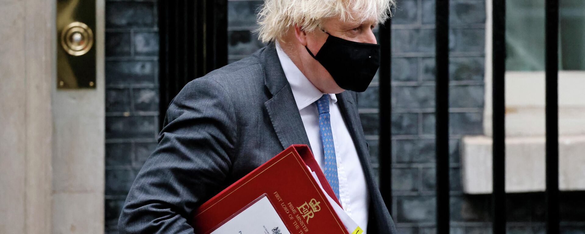 Britain's Prime Minister Boris Johnson, wearing a face covering to stop the spread of coronavirus, carries his notes in a ministerial folder as he leaves from 10 Downing Street in central London on December 15, 2021, to take part in the weekly session of Prime Minister Questions (PMQs) at the House of Commons - Sputnik International, 1920, 16.01.2022
