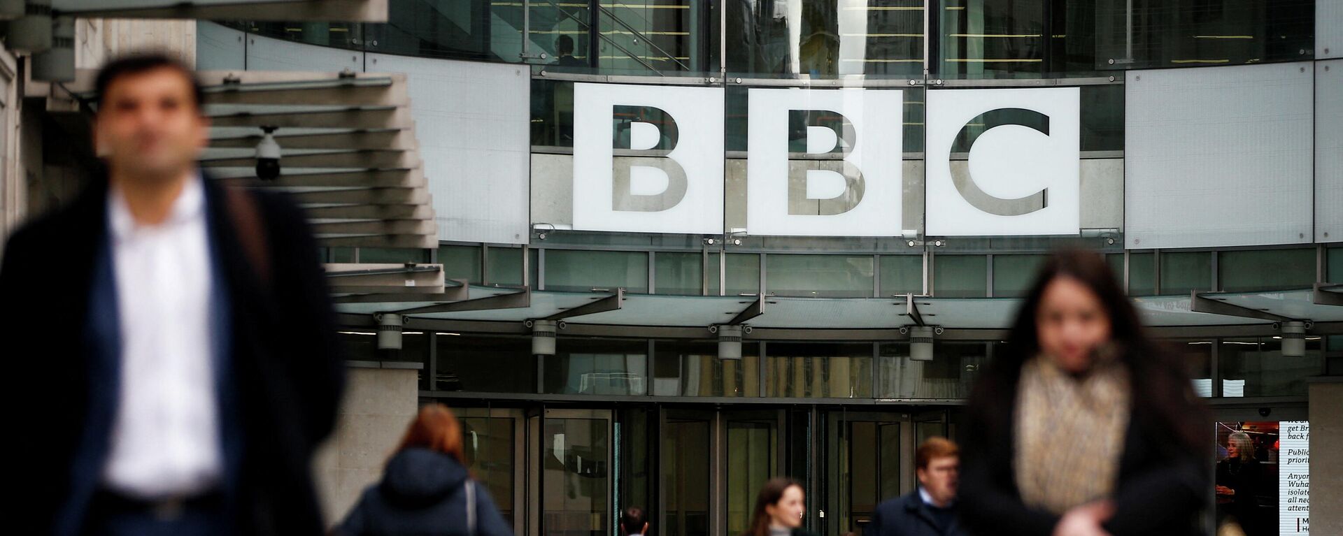 FILE PHOTO: Pedestrians walk past a BBC logo at Broadcasting House, as the corporation announced it will cut around 450 jobs from its news division, in London - Sputnik International, 1920, 16.01.2022