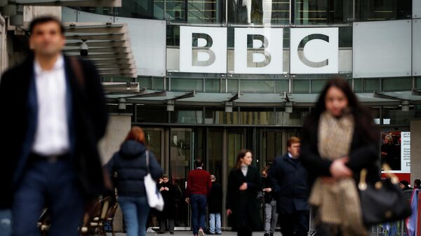 FILE PHOTO: Pedestrians walk past a BBC logo at Broadcasting House, as the corporation announced it will cut around 450 jobs from its news division, in London - Sputnik International
