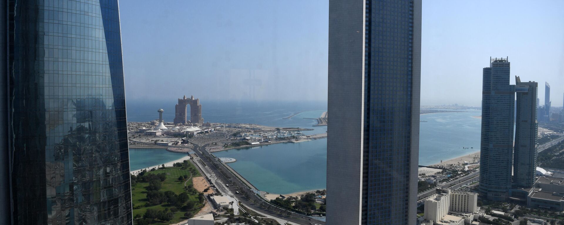 A general view shows the sea front promenade in the Emirati capital Abu Dhabi with the ADNOC headquarters (Abu Dhabi National Oil Company) office complex (C) in the foreground on May 29, 2019. - Sputnik International, 1920, 04.02.2026