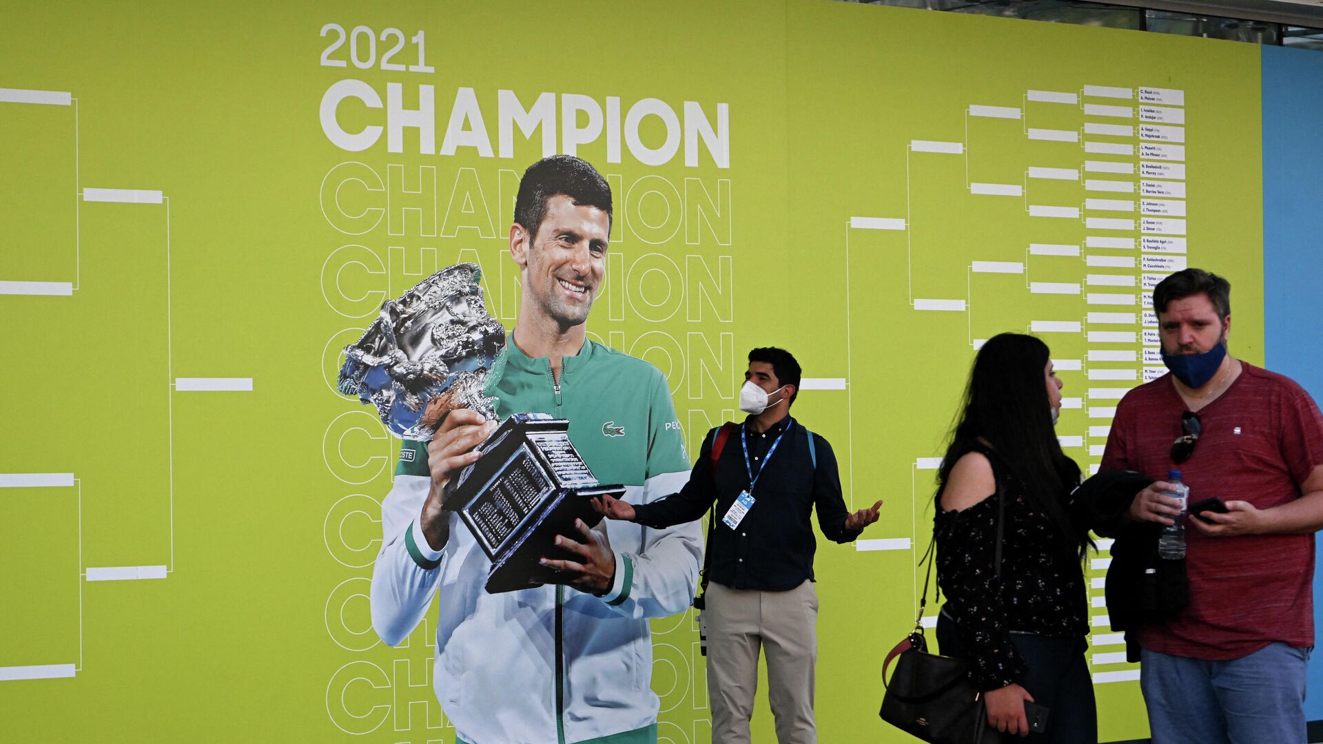 Tennis - Australian Open - Melbourne Park, Melbourne, Australia - January 17, 2022 People are seen in front of an image of Novak Djokovic on the first day of the Australian Open at Melbourne Park - Sputnik International, 1920, 17.01.2022