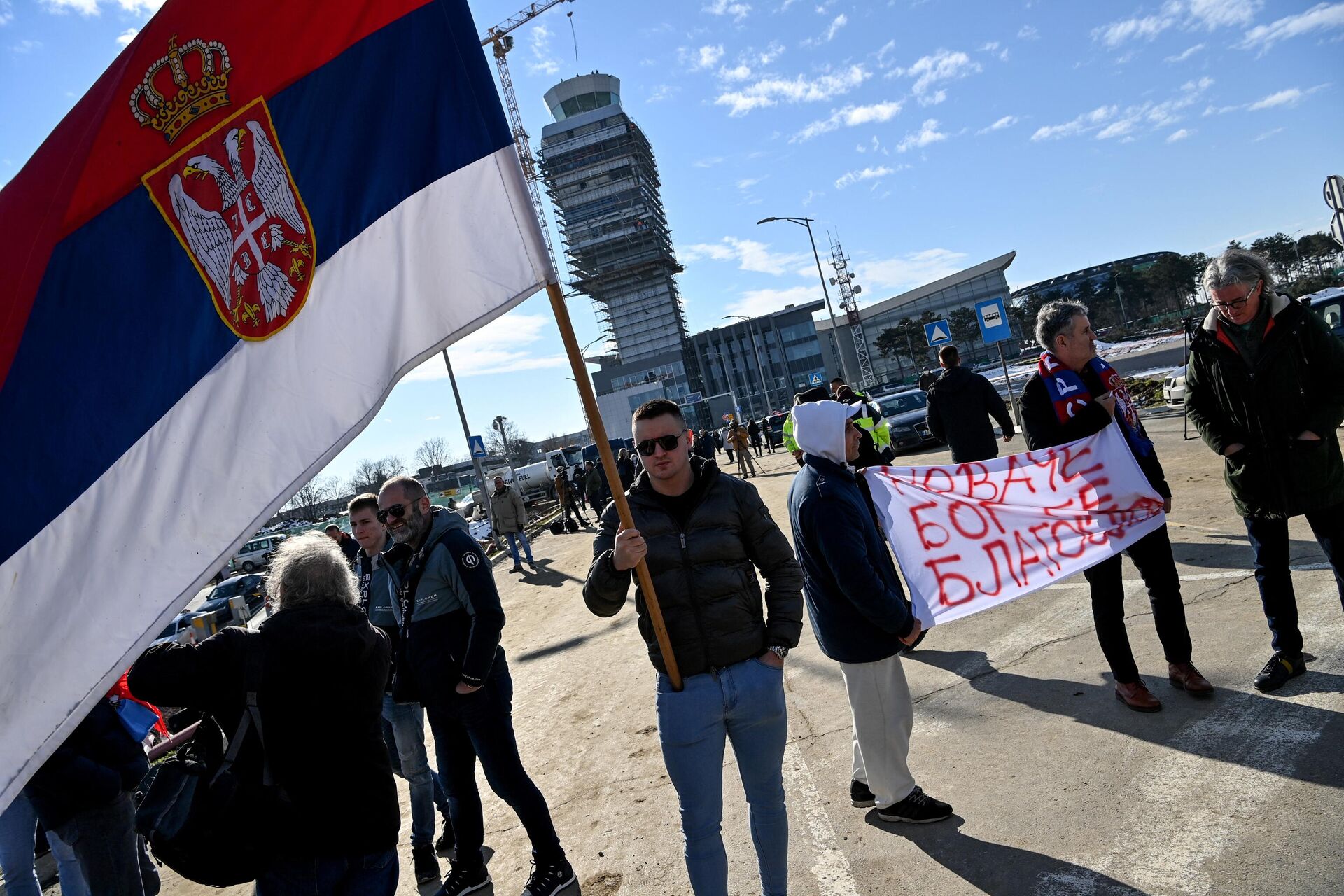 People hold a banner reading Novak, God bless you and another holds a Serbian national flag as they wait outside the VIP exit of Belgrade's international airport on 17 January 2022, for Tennis world number one Novak Djokovic's arrival after his deportation from Australia over his coronavirus vaccination status. - Sputnik International, 1920, 20.01.2022