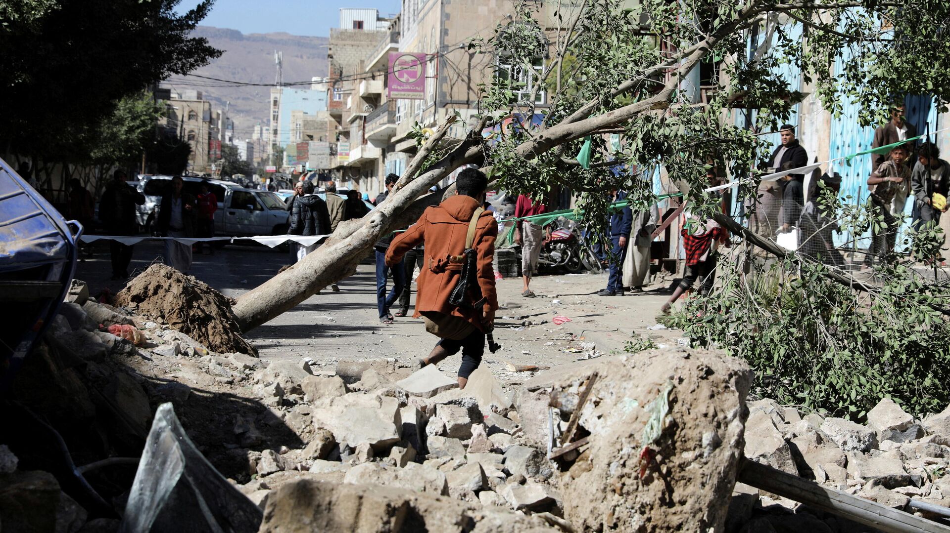 An armed man walks at the site of a Saudi-led air strike in Sanaa, Yemen December 24, 2021 - Sputnik International, 1920, 17.01.2022