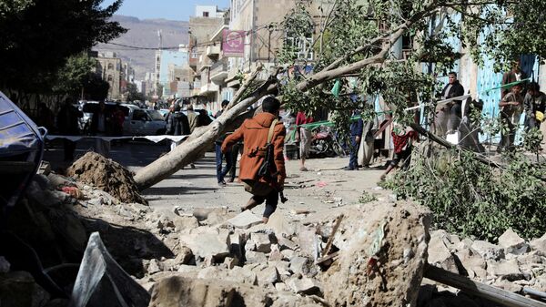 An armed man walks at the site of a Saudi-led air strike in Sanaa, Yemen December 24, 2021 - Sputnik International