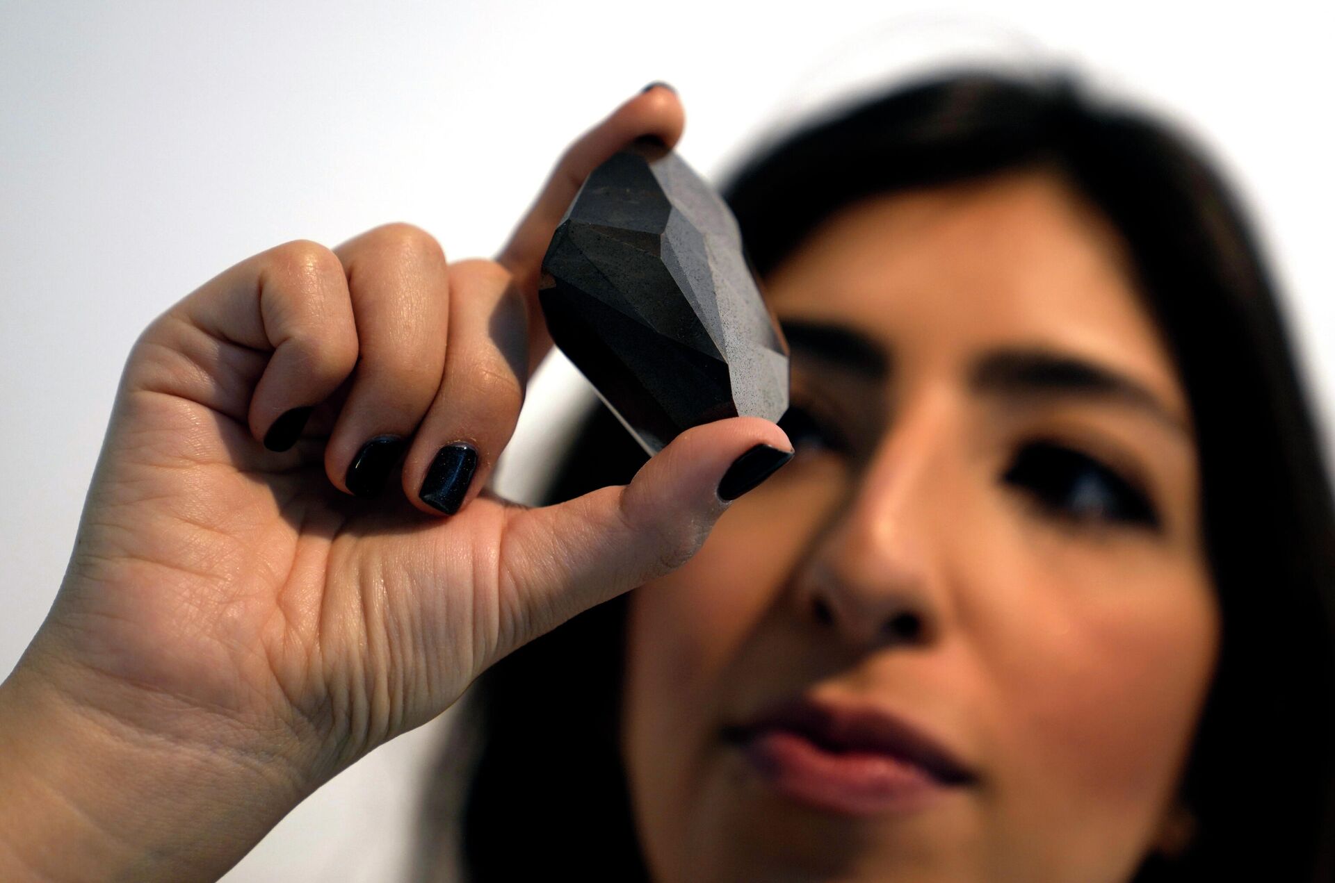 An employee of Sotheby's Dubai presents a 555.55 Carat Black Diamond The Enigma to be auctioned at Sotheby's Dubai gallery, in Dubai, United Arab Emirates, Monday, Jan. 17, 2022. - Sputnik International, 1920, 18.01.2022