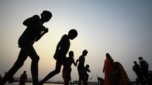 Hindu devotees walk after taking a holy dip in the waters of Sangam, the confluence of the Ganges, Yamuna and Saraswati rivers during Magh Mela festival, amidst the spread of the coronavirus disease (COVID-19) in Prayagraj, India, January 14, 2022 - Sputnik International