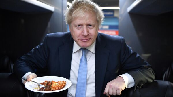 Britain's Prime Minister Boris Johnson eats a portion of pie aboard the Conservative Party campaign bus after a visit to the Red Olive catering company in Derby, central England Wednesday Dec. 11, 2019.  - Sputnik International