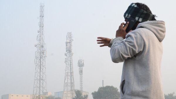 A man talks on his mobile phone near a telecom tower, on the outskirts of Amritsar on December 30, 2020 - Sputnik International