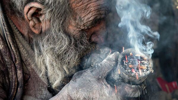 Amou Haji (uncle Haji) smokes from his waterpipe as he sits on the ground on the outskirts of the village of Dezhgah in the Dehram district of the southwestern Iranian Fars province, on December 28, 2018 - Sputnik International