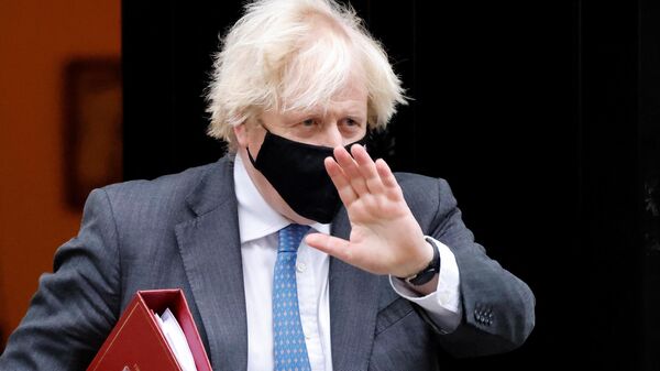 Britain's Prime Minister Boris Johnson, wearing a face covering to stop the spread of coronavirus, waves as he leaves from 10 Downing Street in central London on December 15, 2021, to take part in the weekly session of Prime Minister Questions (PMQs) at the House of Commons - Sputnik International