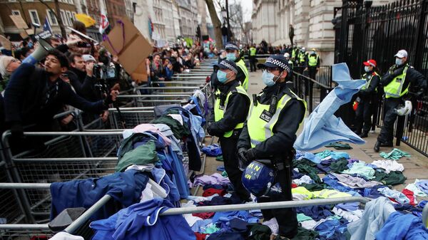 Police officers stand amid the NHS uniforms thrown by NHS staff and others protesting against the coronavirus disease (COVID-19) vaccine rules at the entrance to Downing Street in London, Britain, January 22, 2022 - Sputnik International