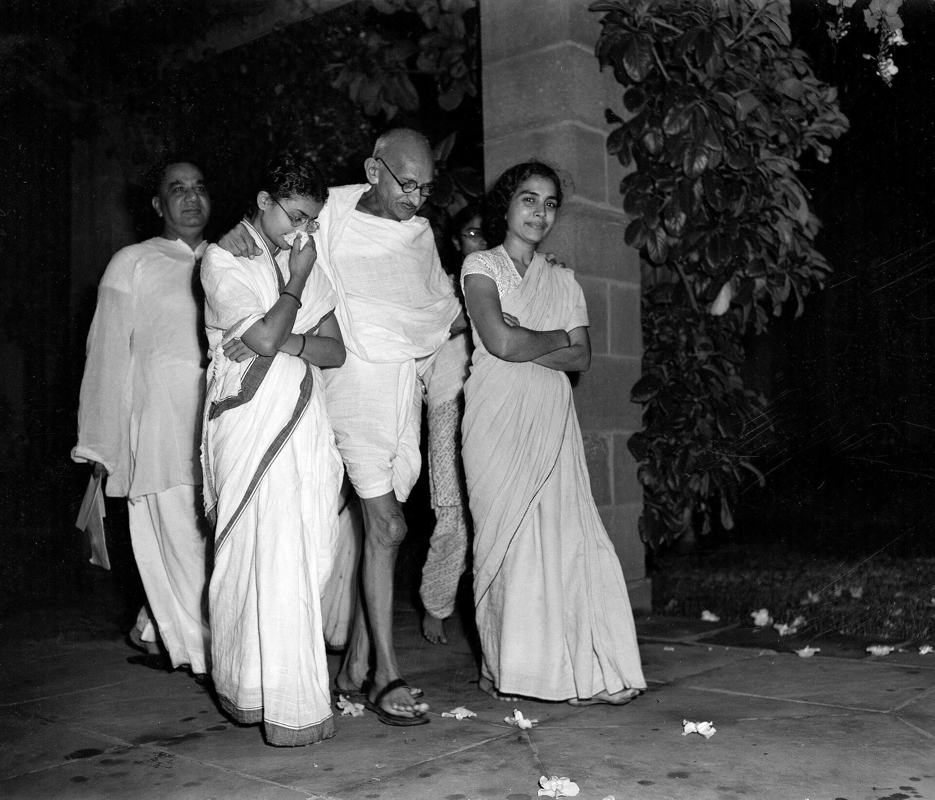 Mahatma Gandhi, center, accompanied by Abha Gandhi, left, and Dr. Sushila Nayyar, right, one of his attendants during his present illness, is shown walking in the garden of Birla House, New Delhi, India, October 2, 1947, as he celebrates his 78th birthday. H.S. Suhrawardy, former chief minister of Bengal Province, is at extreme left, rear - Sputnik International, 1920, 14.08.2022