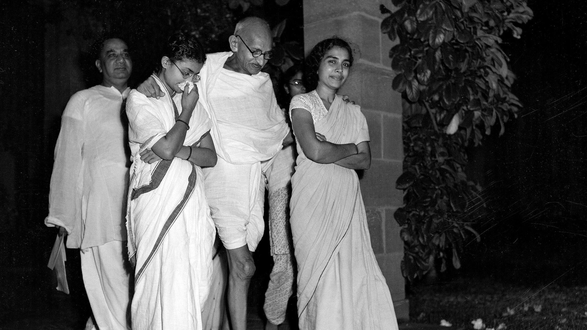 Mahatma Gandhi, center, accompanied by Abha Gandhi, left, and Dr. Sushila Nayyar, right, one of his attendants during his present illness, is shown walking in the garden of Birla House, New Delhi, India, October 2, 1947, as he celebrates his 78th birthday. H.S. Suhrawardy, former chief minister of Bengal Province, is at extreme left, rear - Sputnik International, 1920, 25.01.2022