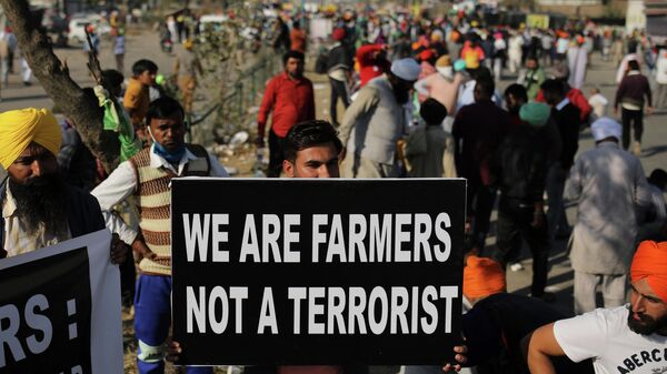 A protesting farmer holds a placard on a major highway at the Delhi-Haryana state border, India, Saturday, Nov. 28, 2020. India’s Prime Minister Narendra Modi made a surprise announcement Friday, Nov. 19, 2021. that he will withdraw the controversial agriculture laws that prompted yearlong farmer protests, in what is seen as a major climbdown from his government. - Sputnik International