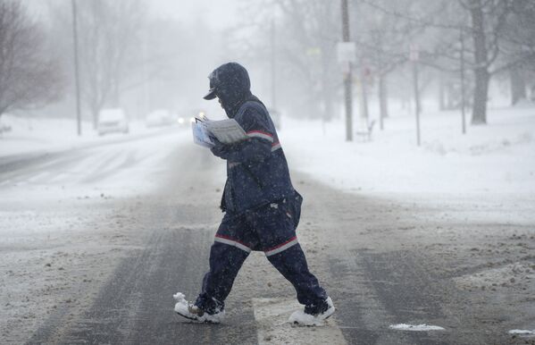 A US Postal Service carrier trudges across the intersection of Downing Street and Louisiana as a winter storm drops several inches of snow Tuesday, 25 January 2022 in Denver. - Sputnik International